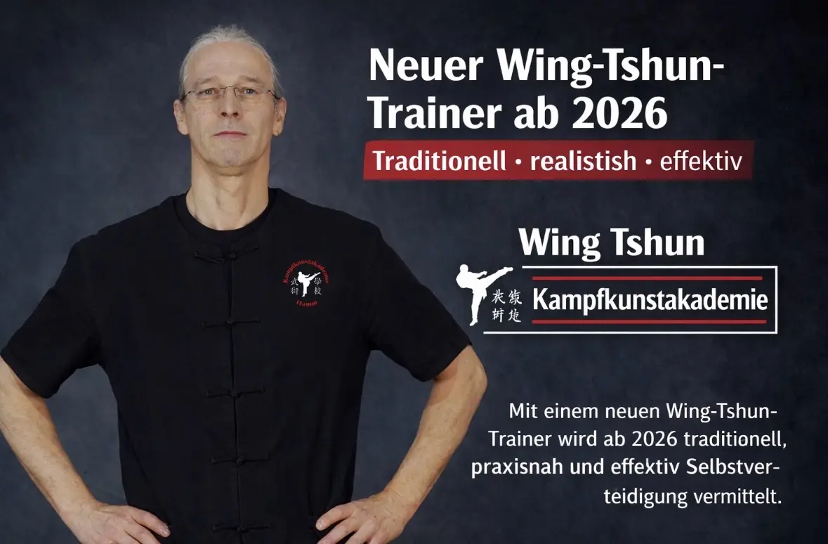 Mann in schwarzem Wing-Tshun-Trainer-Outfit mit Logo der Kampfkunstakademie, steht vor neutralem Hintergrund.