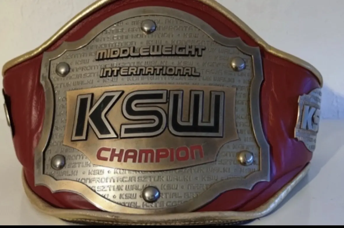 Roter KSW-Champion-Gürtel mit metallener Platte und der Aufschrift „KSW Champion“ sowie „Middleweight International“